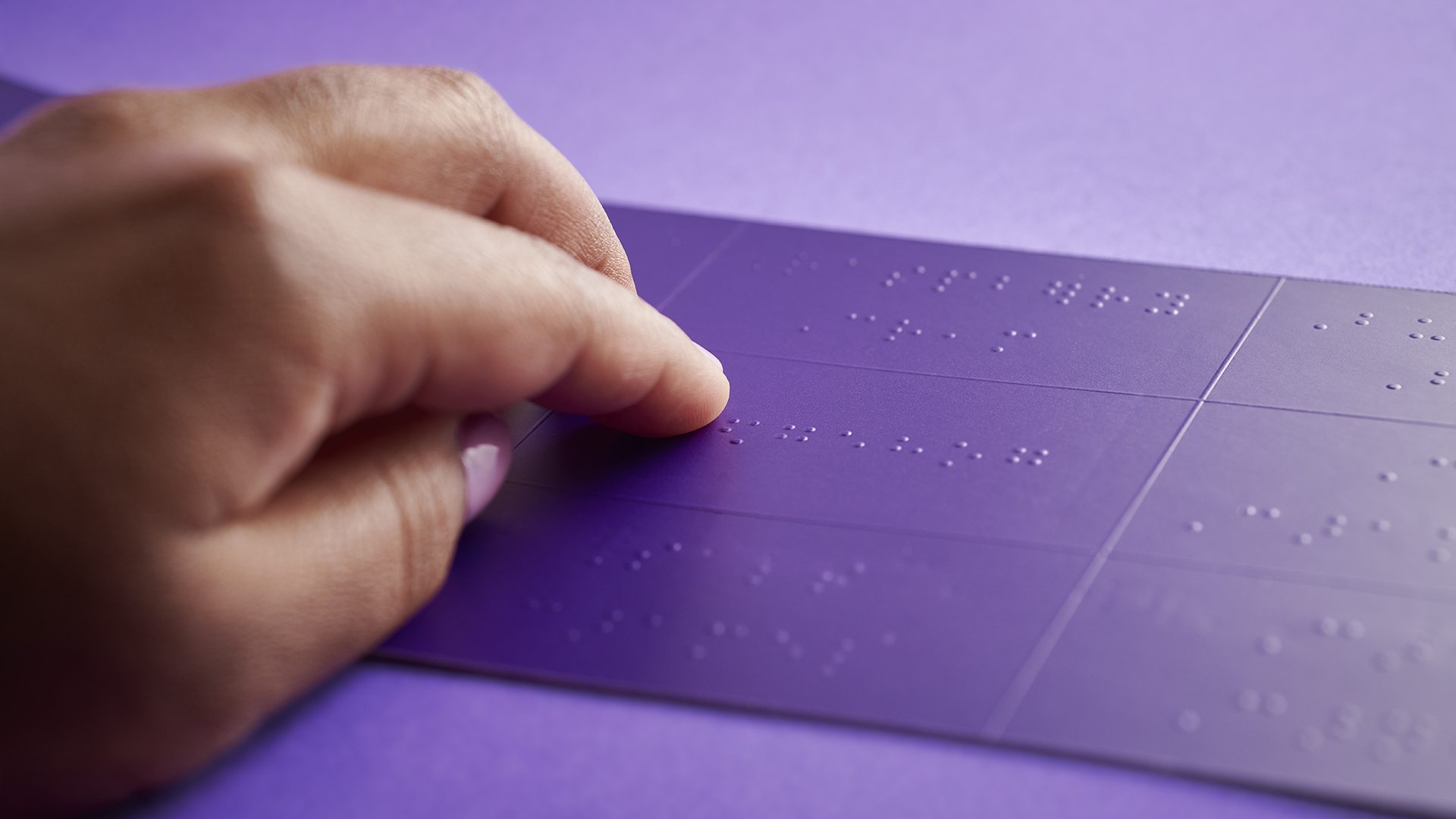 Anne's fingers navigating the raised purple braille on the chocolate legent for The Purdys Holiday Braille Box