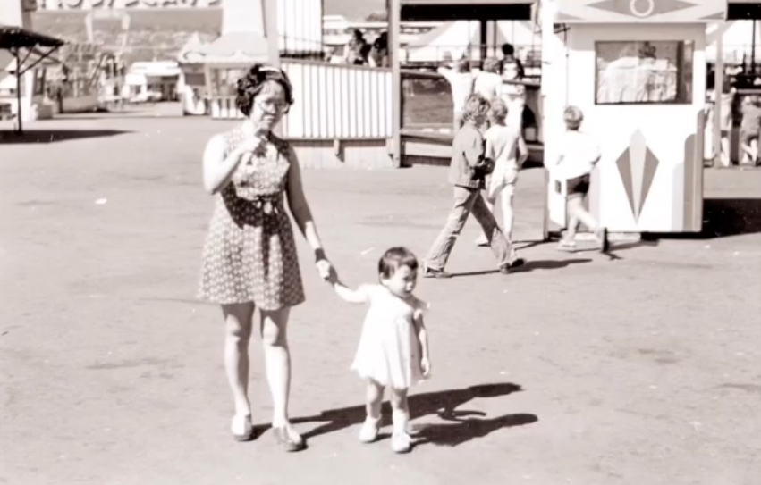 Black and white photo of Anne, an Asian woman, at approx 3 years old with her mother in a amusement park.